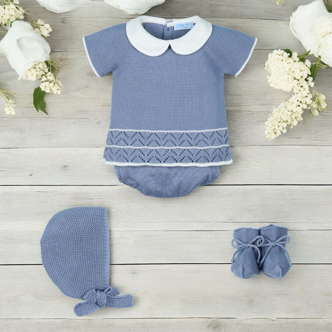 Dusky baby outfit with matching hat and shoes on a wooden surface with flowers.