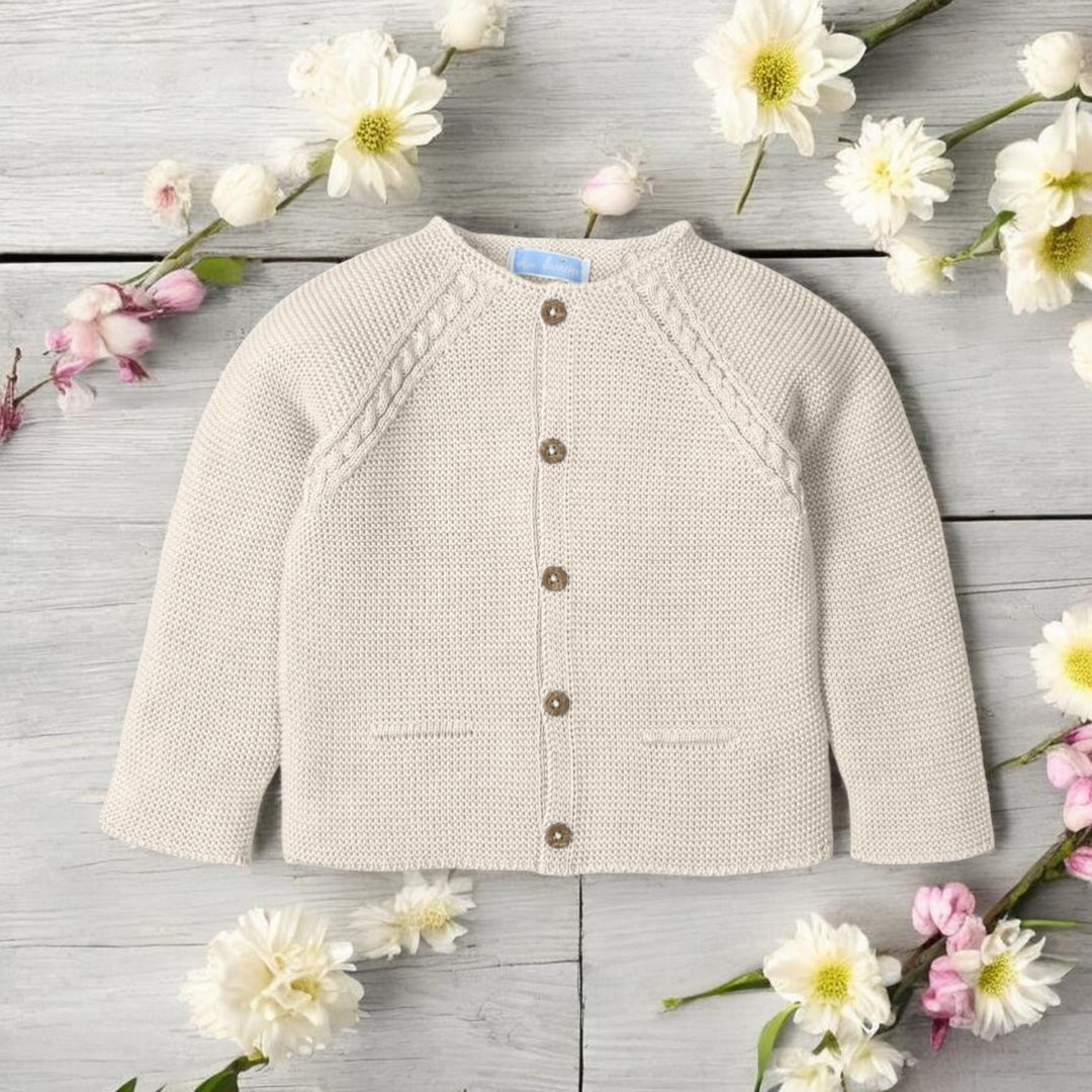 Baby sweater on a wooden surface with flowers around